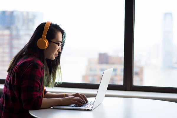 Alum wearing headphones and using laptop